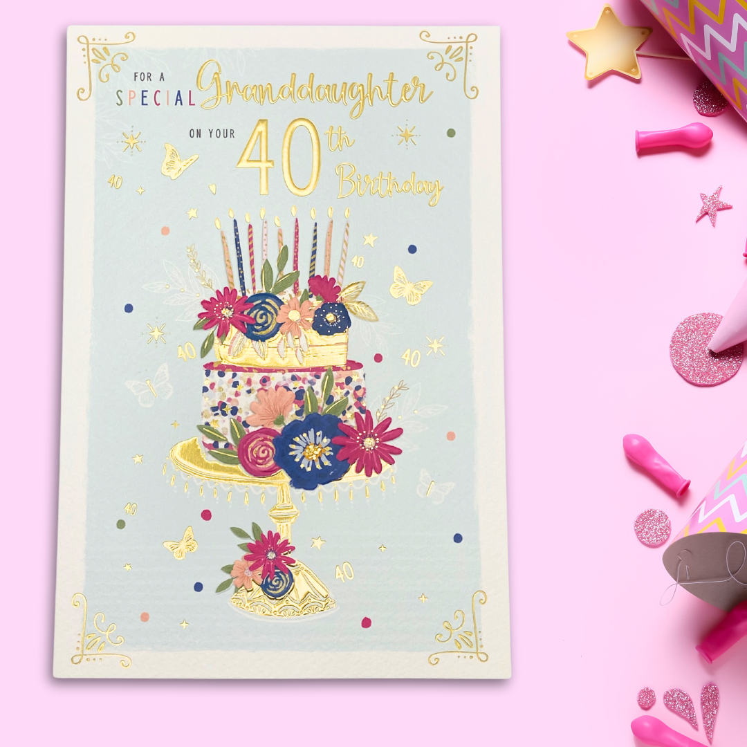 White card with pink and blue stacked cake with candles and floral accents with butterflies and text in gold foil