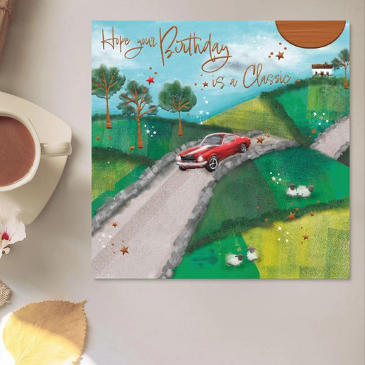 Square card with a red classic car on country road