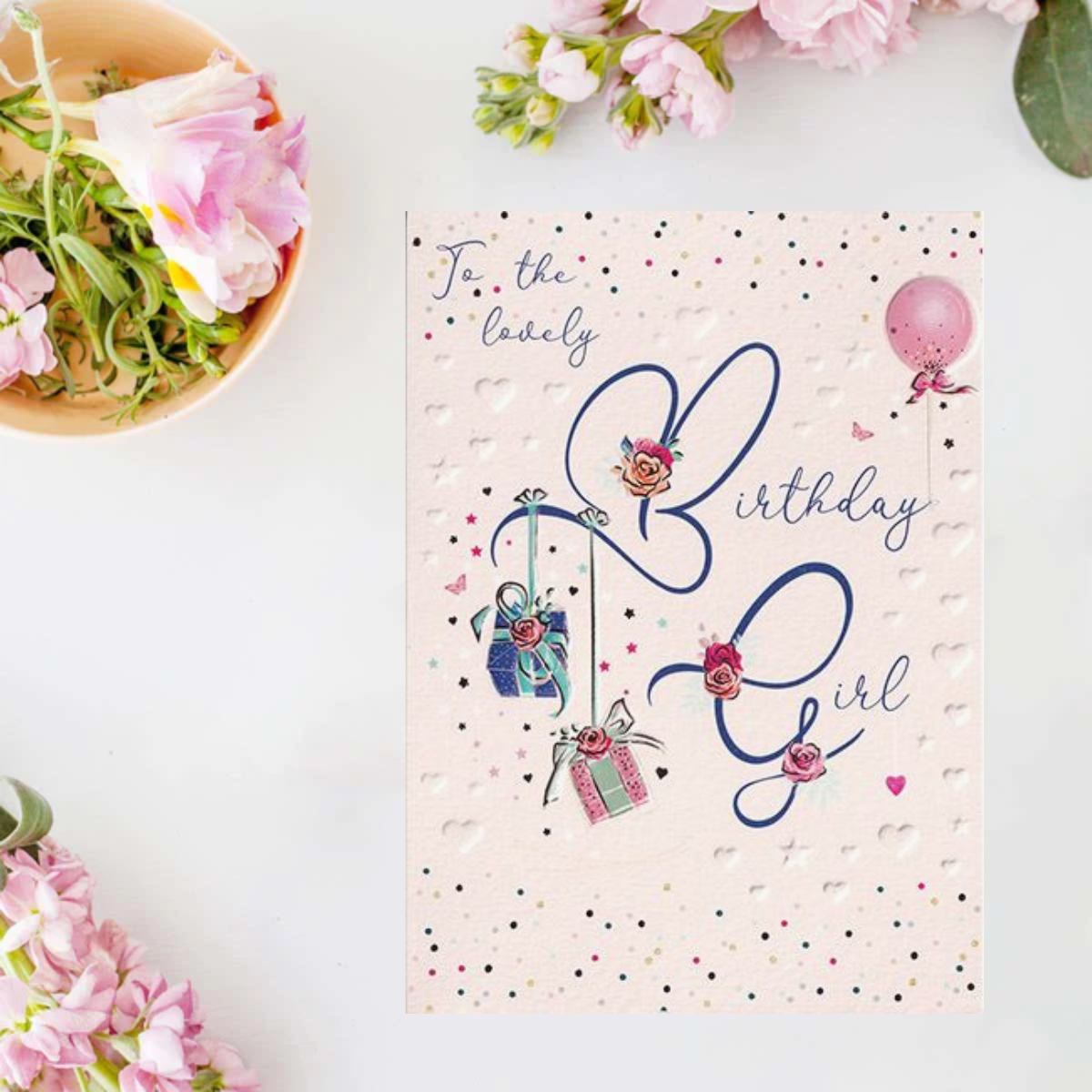 Pink card with embossed stars and hearts, blue script text and floral presents