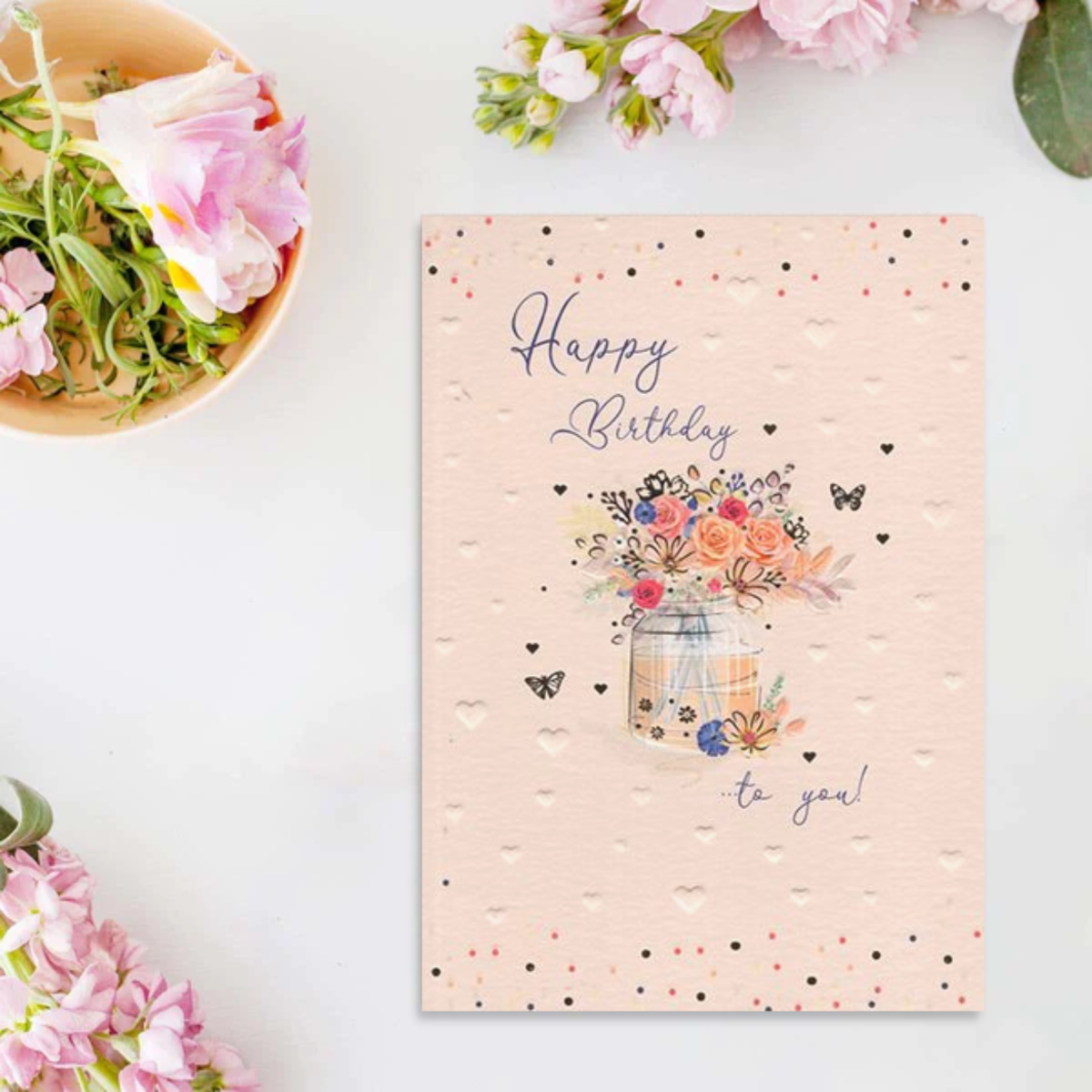 Peach colour card with embossed hearts, vase of flowers and blue script text