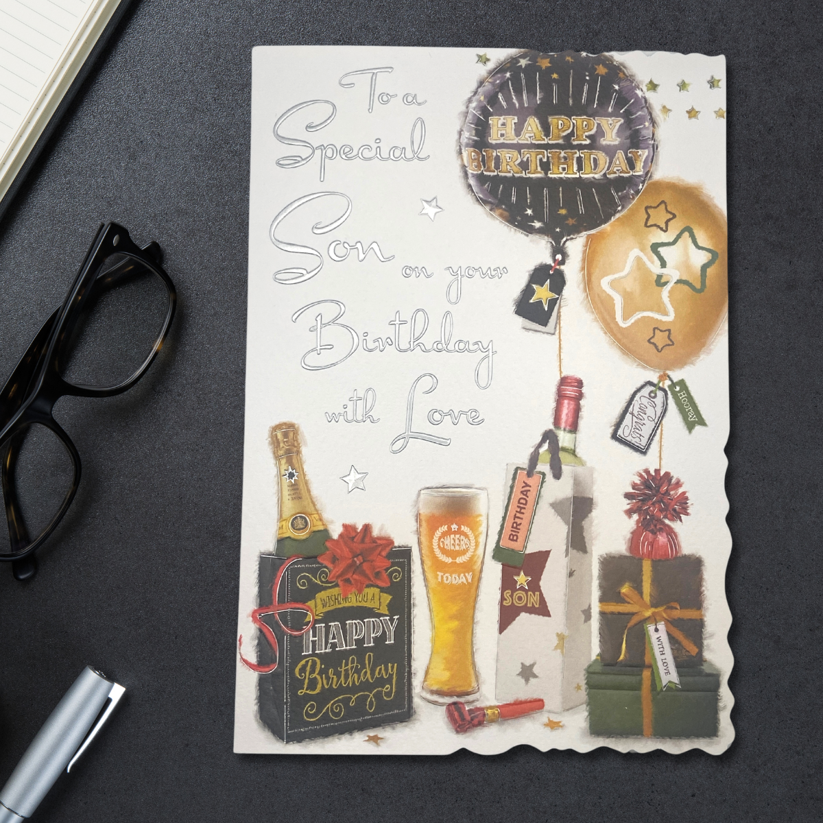 White card with black and gold theme balloons and gifts with beer and bubbly