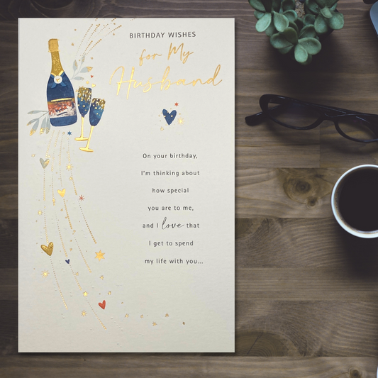 Large card with gold foil text, blue and gold bottle of bubbly and flutes