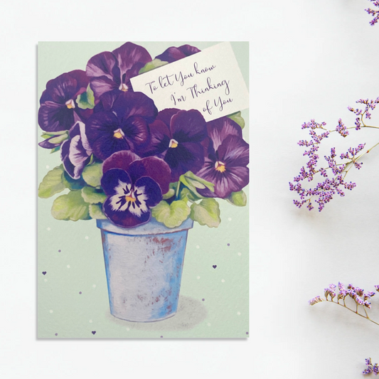 Front image showing pot of purple pansies with card and greeting