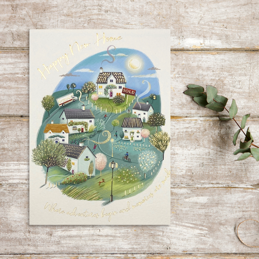 White card with village sketch image and gold foil text around border