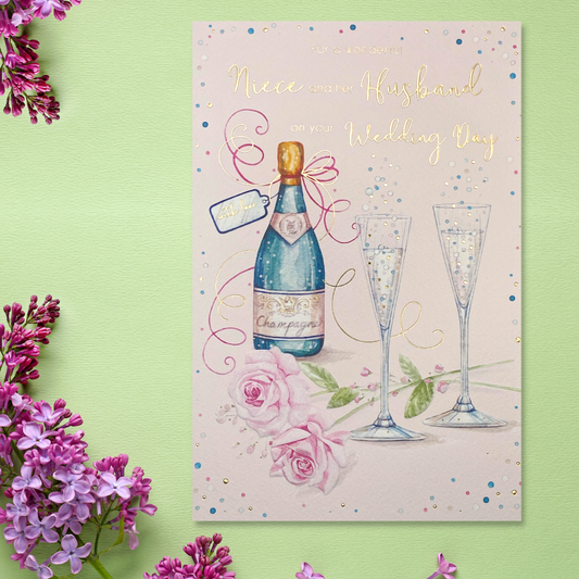 Pink card with bottle of champagne, flutes and flowers. with gold foil fetails