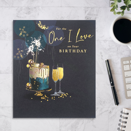 Square navy card with green and cream cake with gold flutes and sparklers and balloons