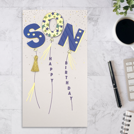 Slim white card with balloons that spell Son in blue and gold decoupage elements. Tassels and gems