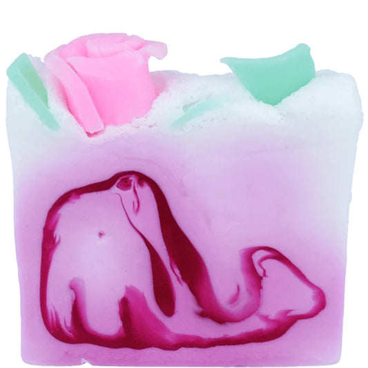 Kiss From A Rose soap slice from Bomb cosmetics with lavender and rose essential oils. Pale pink with swirls of darker pink and topped with a pink rose and green leaves. Glycerin soap and vegan friendly.