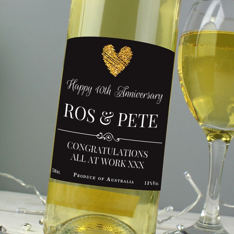 Bottle of white wine with a personalised label next to a glass of wine on a grey background