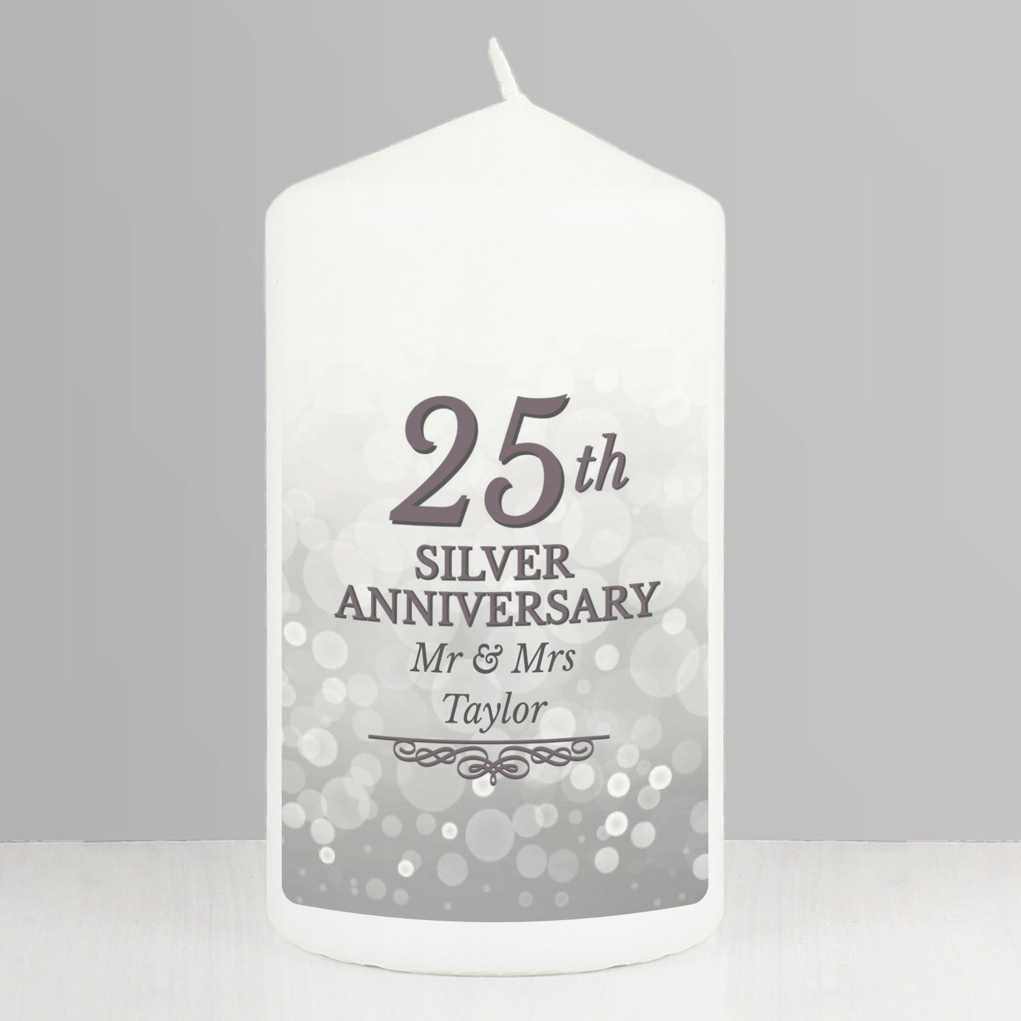 White candle with '25th Silver Anniversary Mr & Mrs Taylor' text on a grey background