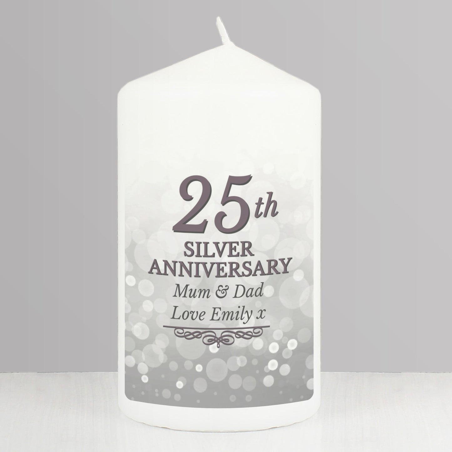 White candle with '25th Silver Anniversary Mum & Dad Love Emily x' text on a gray background