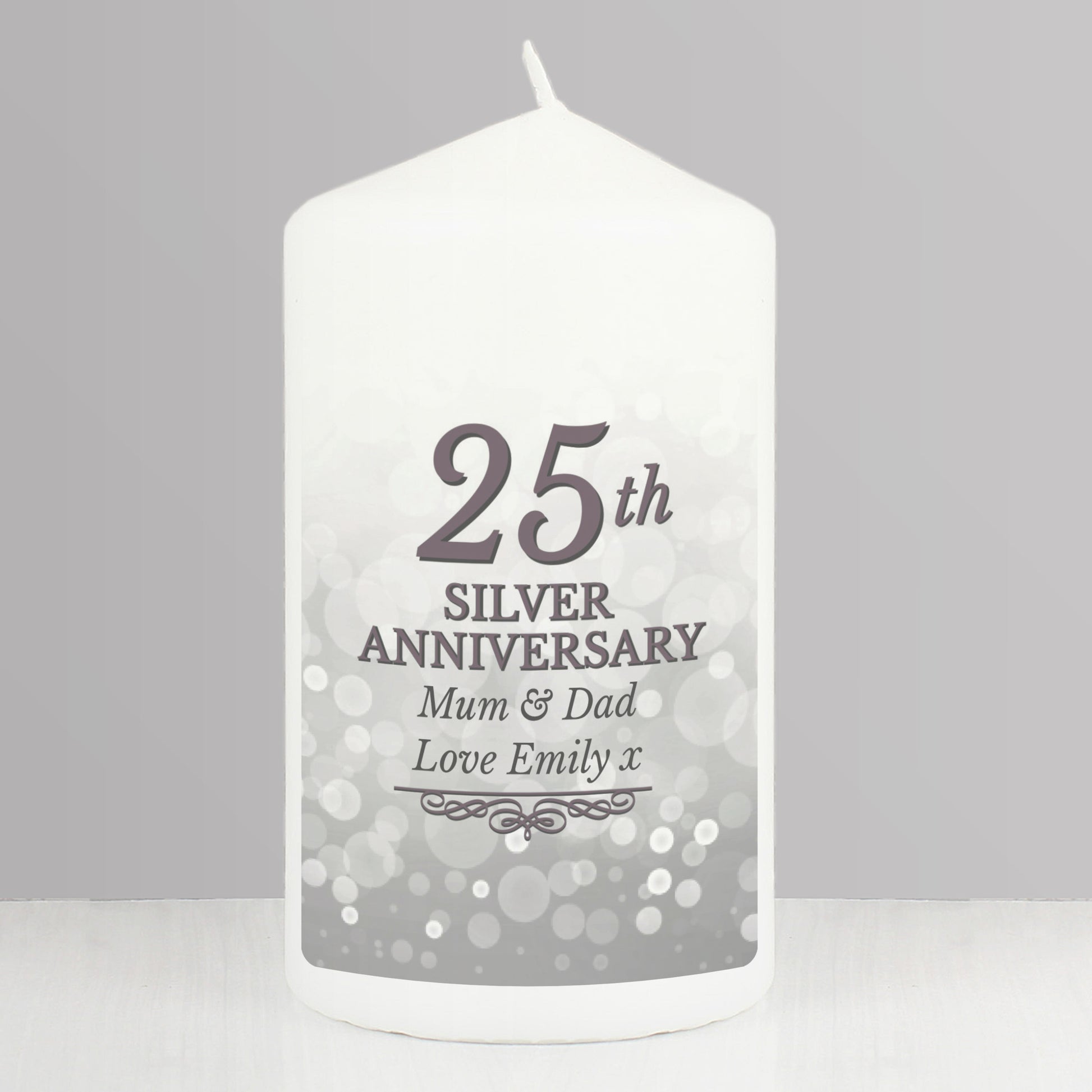 White candle with '25th Silver Anniversary Mum & Dad Love Emily x' text on a gray background
