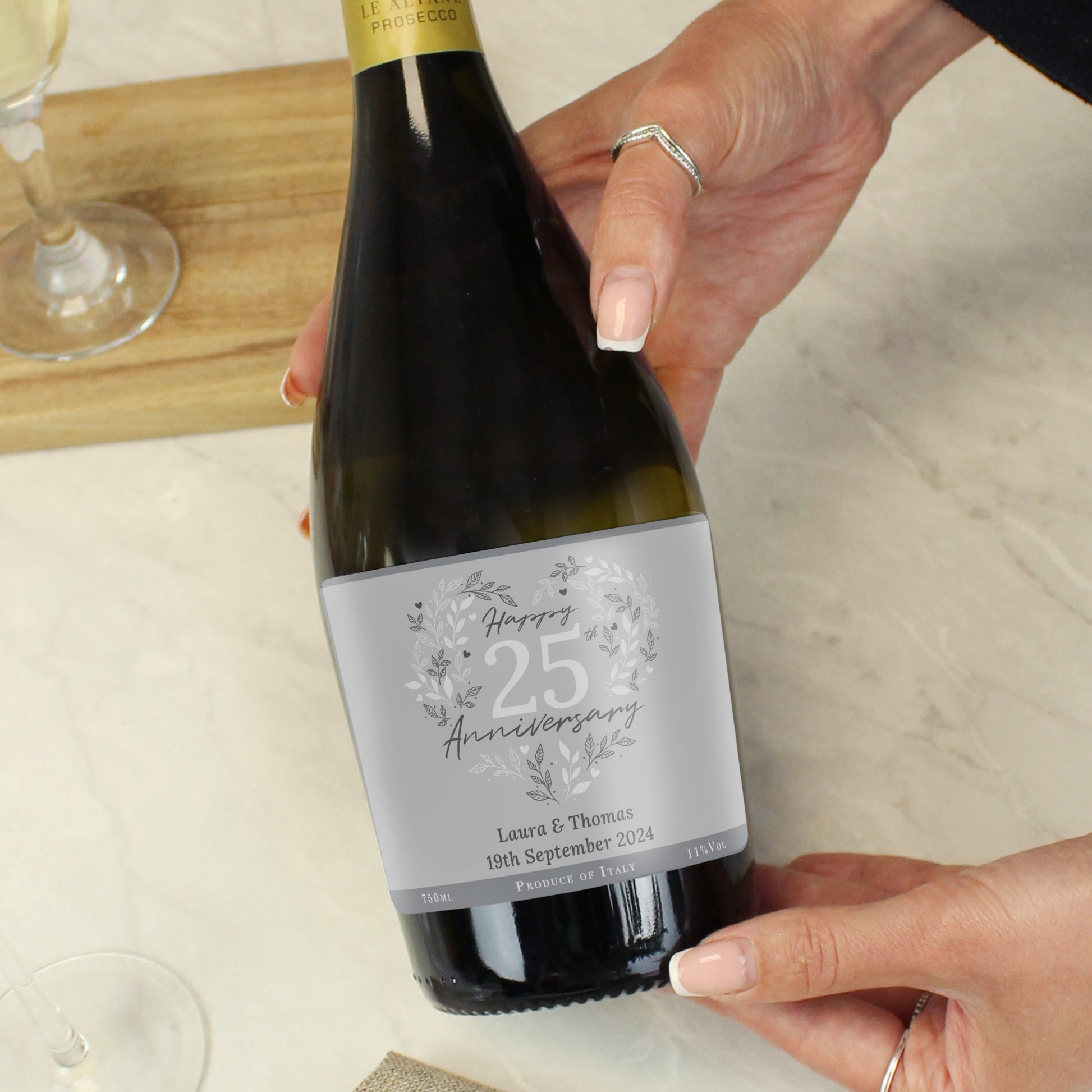 Person holding a wine bottle with a personalised label on a light background