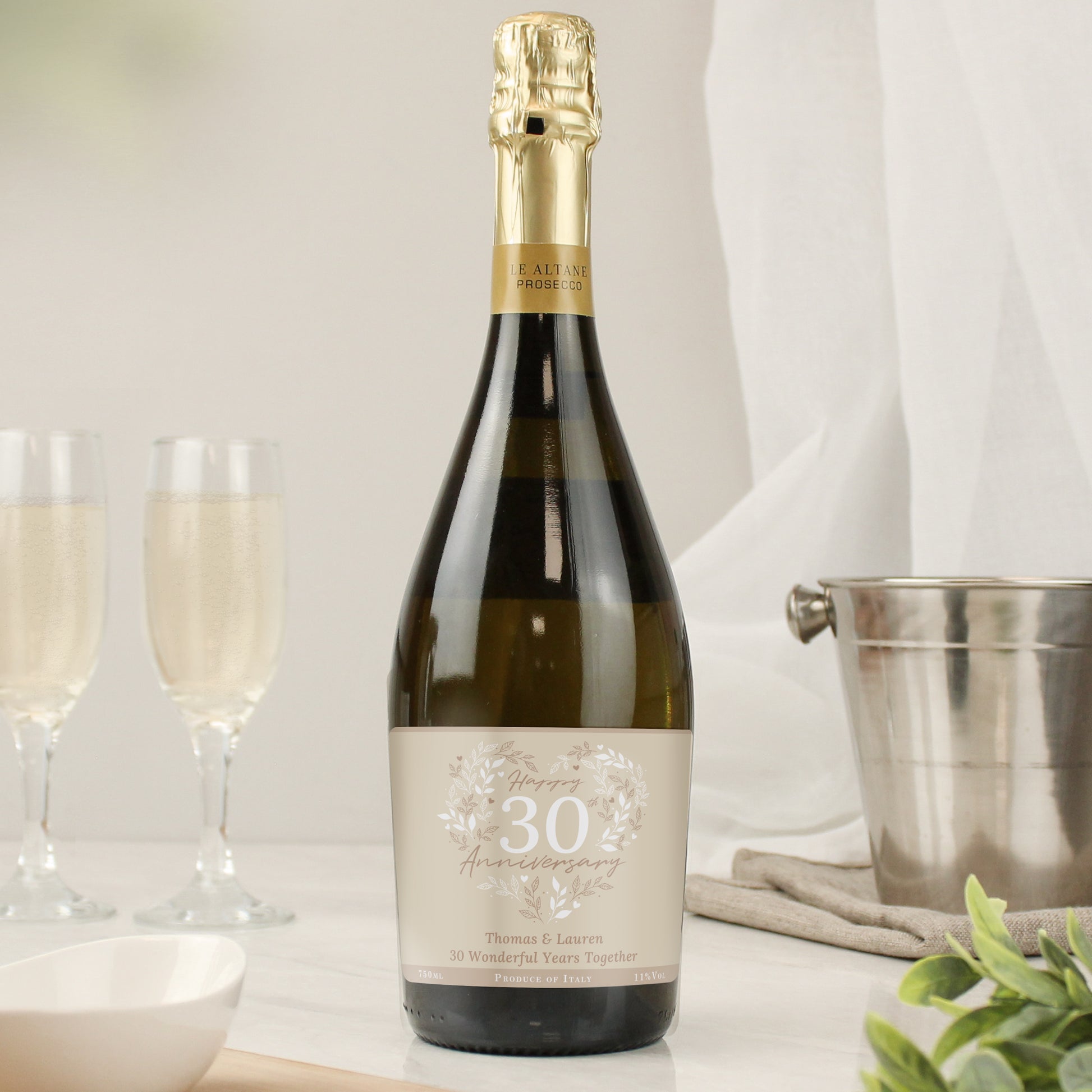 Bottle of champagne with a personalised label next to two glasses on a table.