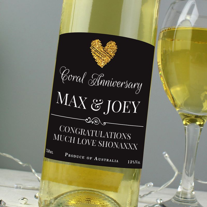 Bottle of white wine with a personalised label next to a glass of wine on a grey background