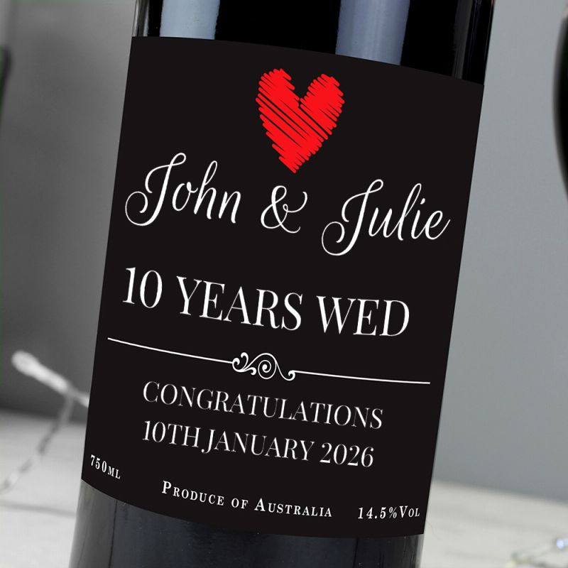 Wine bottle with a personalised label for a 10th wedding anniversary, featuring a red heart and text.