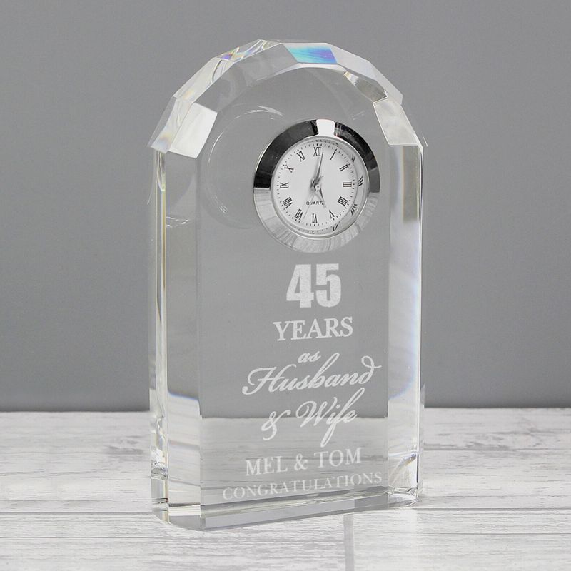 Glass clock with engraved text on a wooden surface