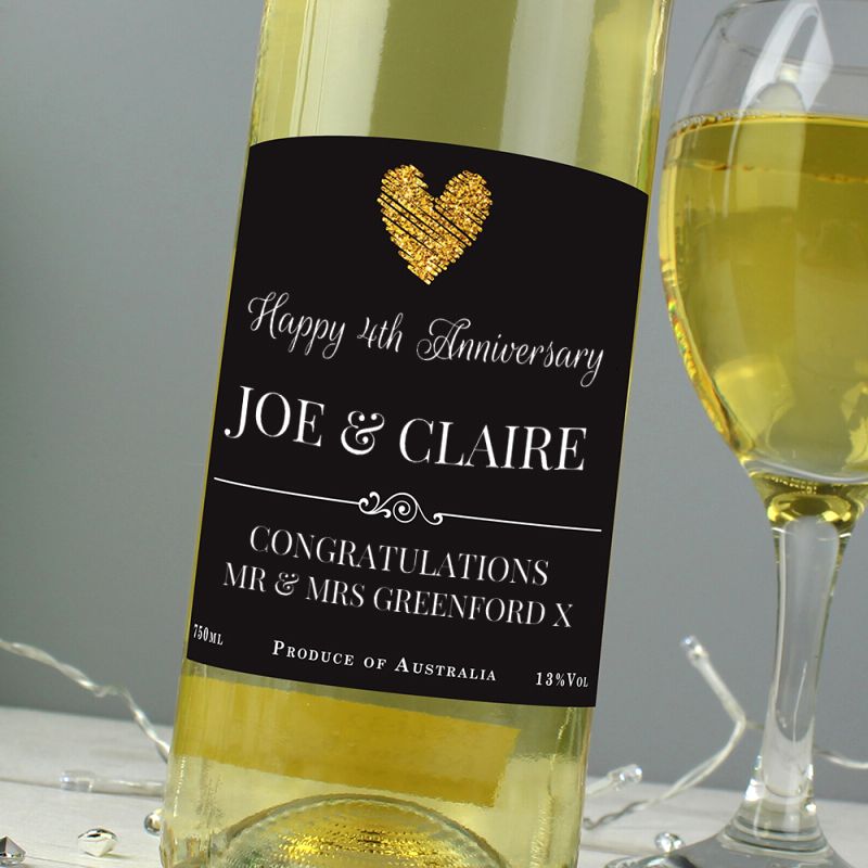 Bottle of white wine with a personalised label for Joe & Claire's 4th anniversary, next to a glass of wine.