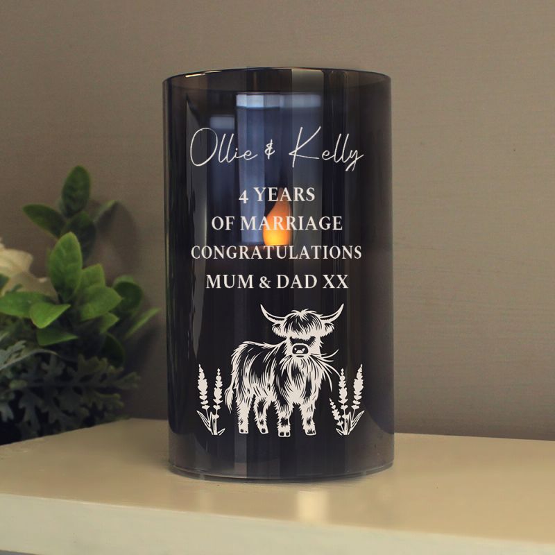 Personalised LED dark glass candle on a shelf next to a plant