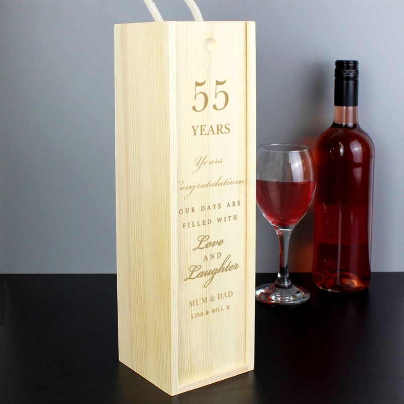 Wooden wine box with engraved message next to a glass and bottle of red wine