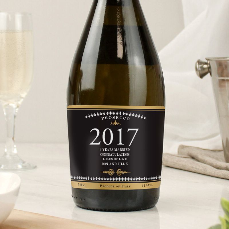 Bottle of Prosecco with a 2017 label on a table with glasses.