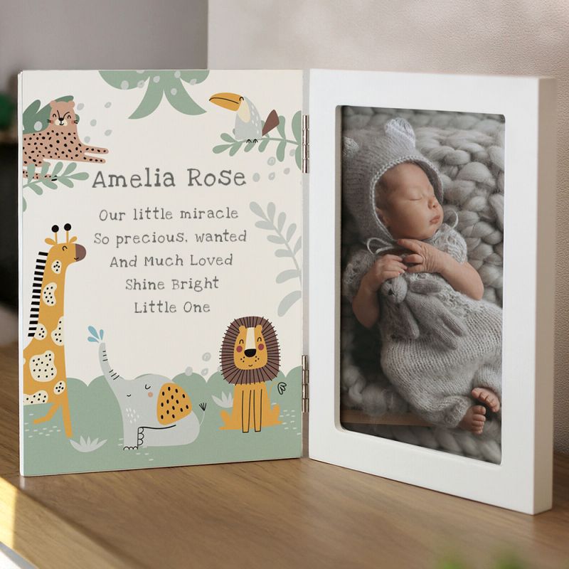 Personalised photo frame with baby's name and animal designs on a wooden surface.
