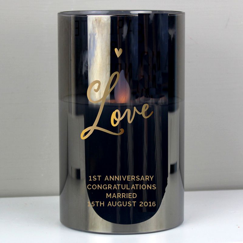 Candle holder with 'Love' and wedding anniversary details on a reflective surface