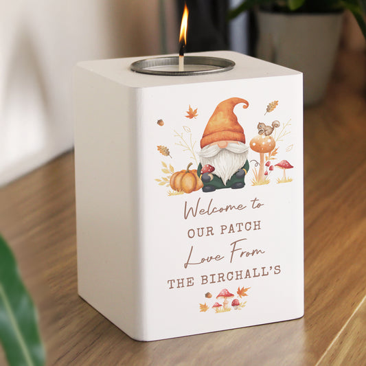 Candle holder with a gnome design and personalised text on a wooden surface.
