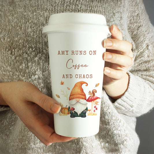 Person holding a white personalised autumn themed travel mug with a gnome design and text.