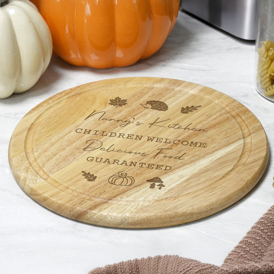 Personalised wooden chopping board with engraved text on a kitchen counter with autumn theme.