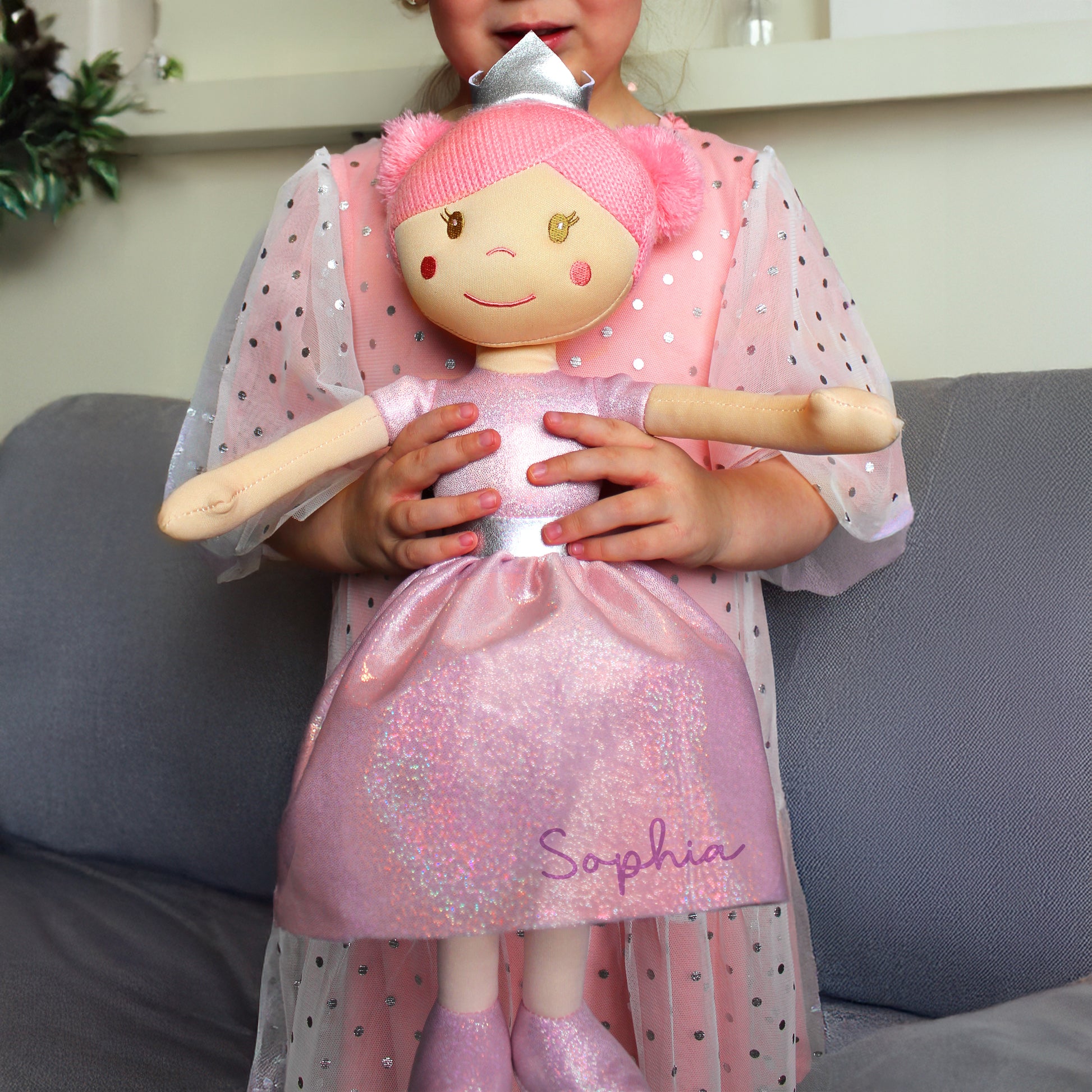 Child holding a doll named 'Sophia' in a pink outfit and shoes.