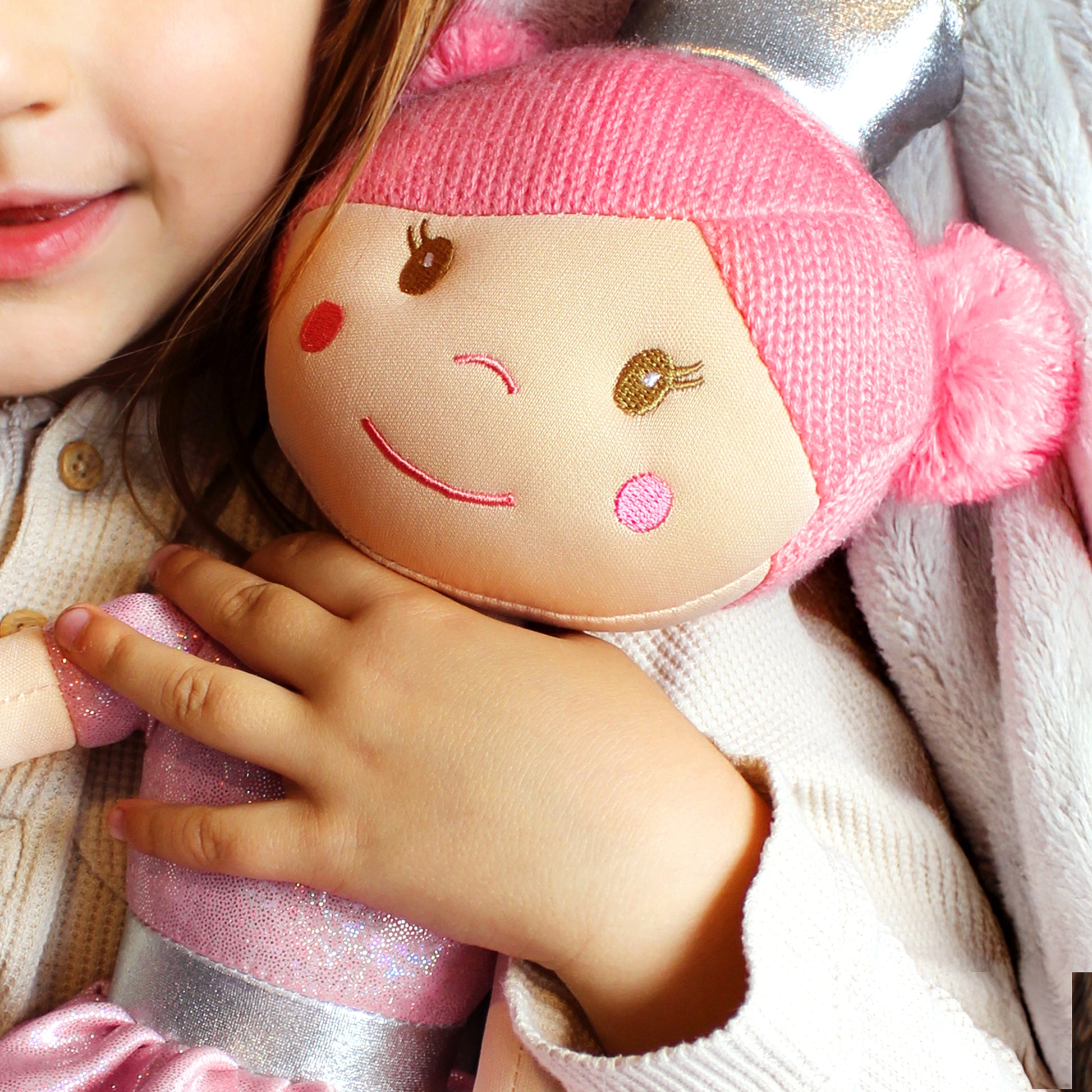 Child holding a plush toy with pink hair and smiling face