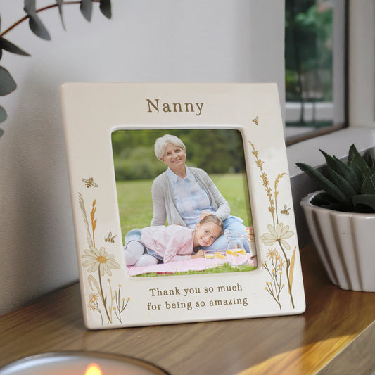 Personalised photo frame with a picture of a woman and a child, placed on a surface with plants in the background.