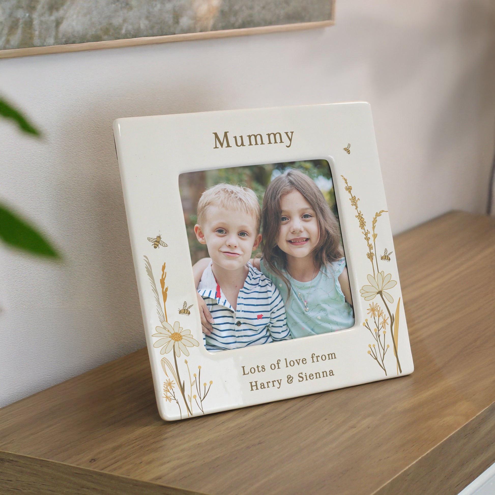 Personalised photo frame with a picture of two children and engraved text on a wooden surface.