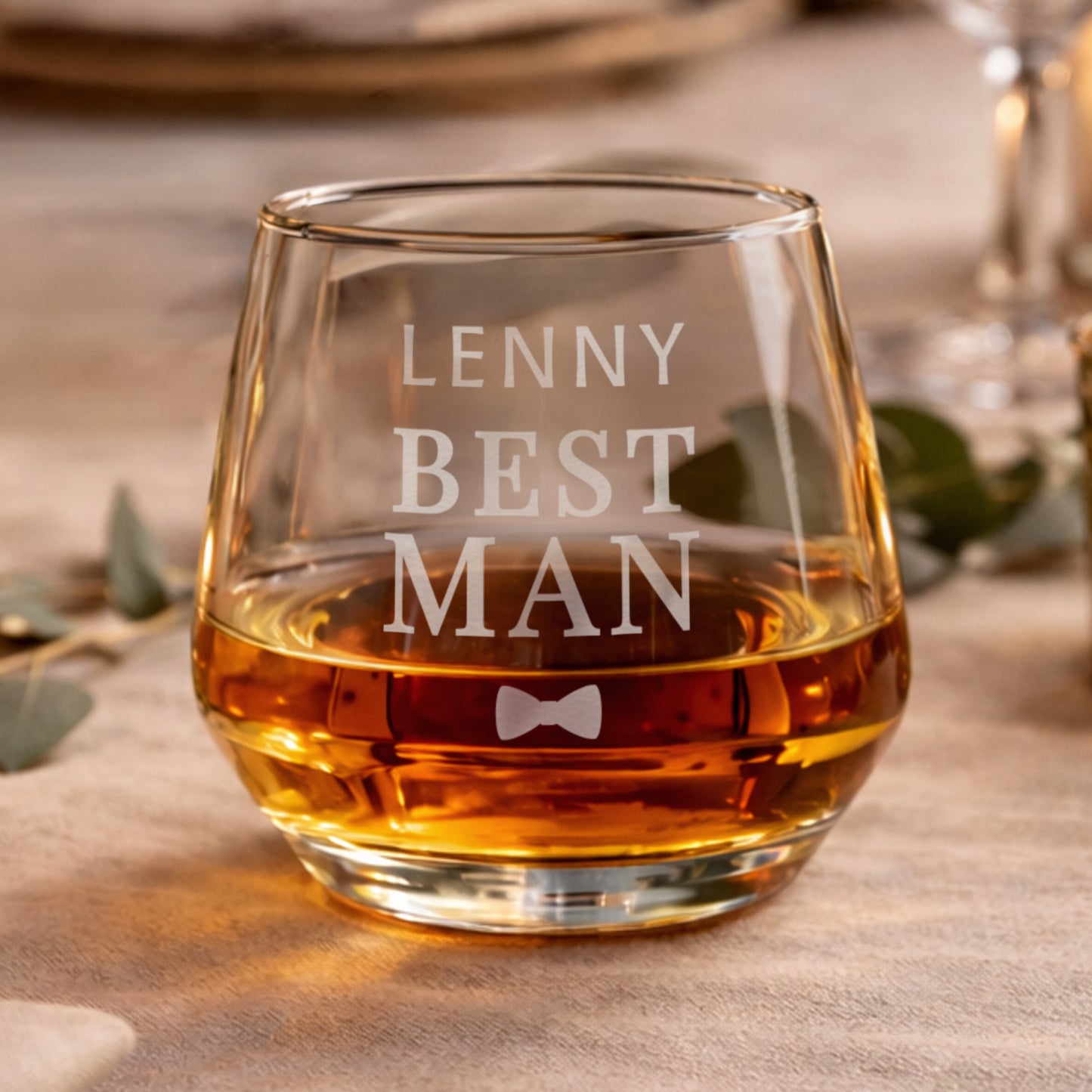 Glass filled with amber liquid, engraved with 'LENNY BEST MAN' text, on a wooden surface.