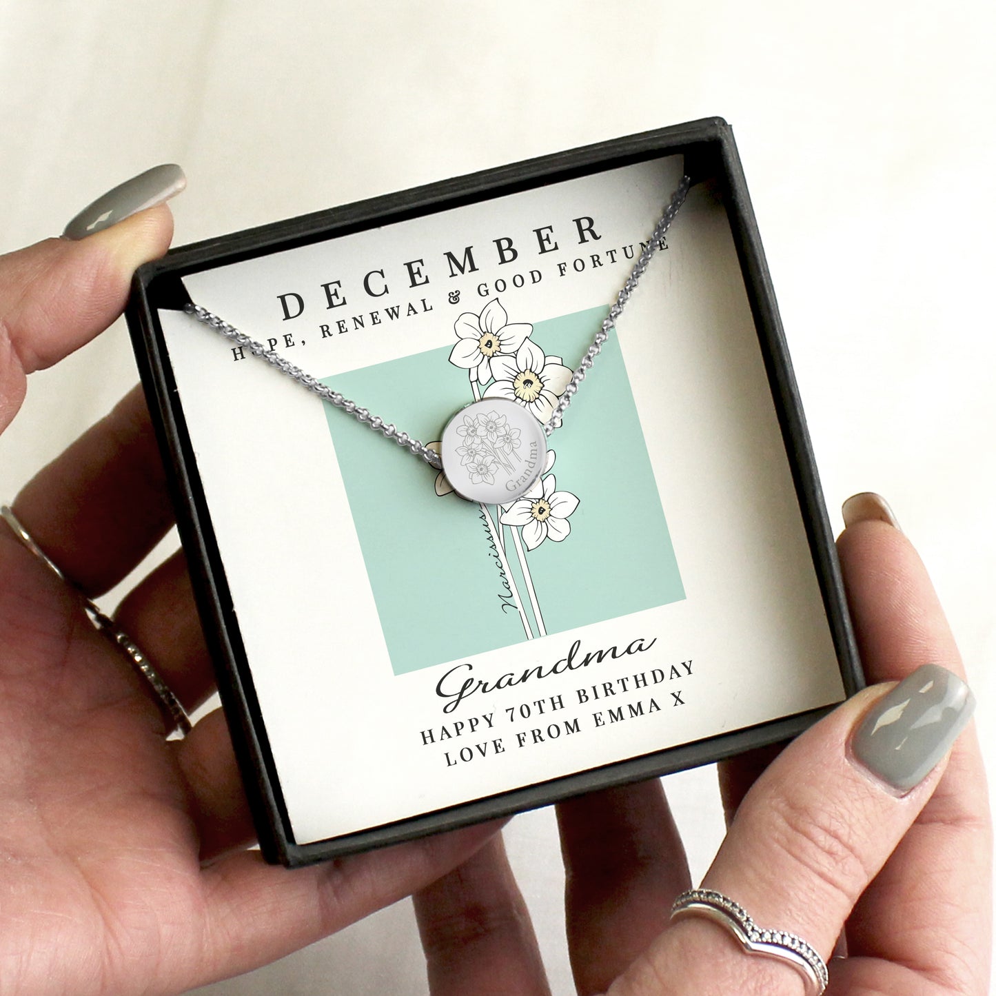 Necklace with floral design in a gift box labeled for a 70th birthday gift to 'Grandma'.