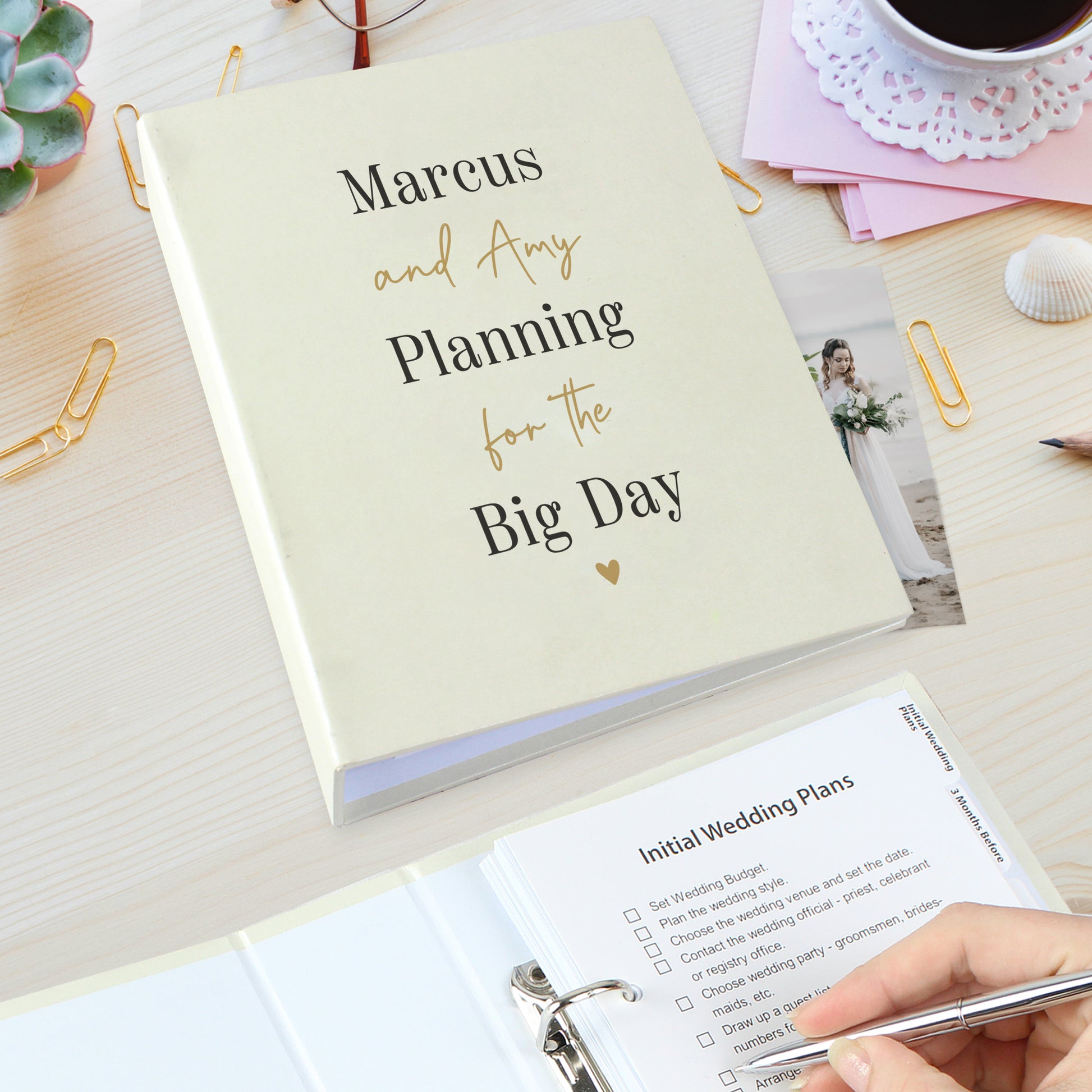 Wedding planning book titled 'Planning for the Big Day' with a hand holding a pen and a checklist on a desk.