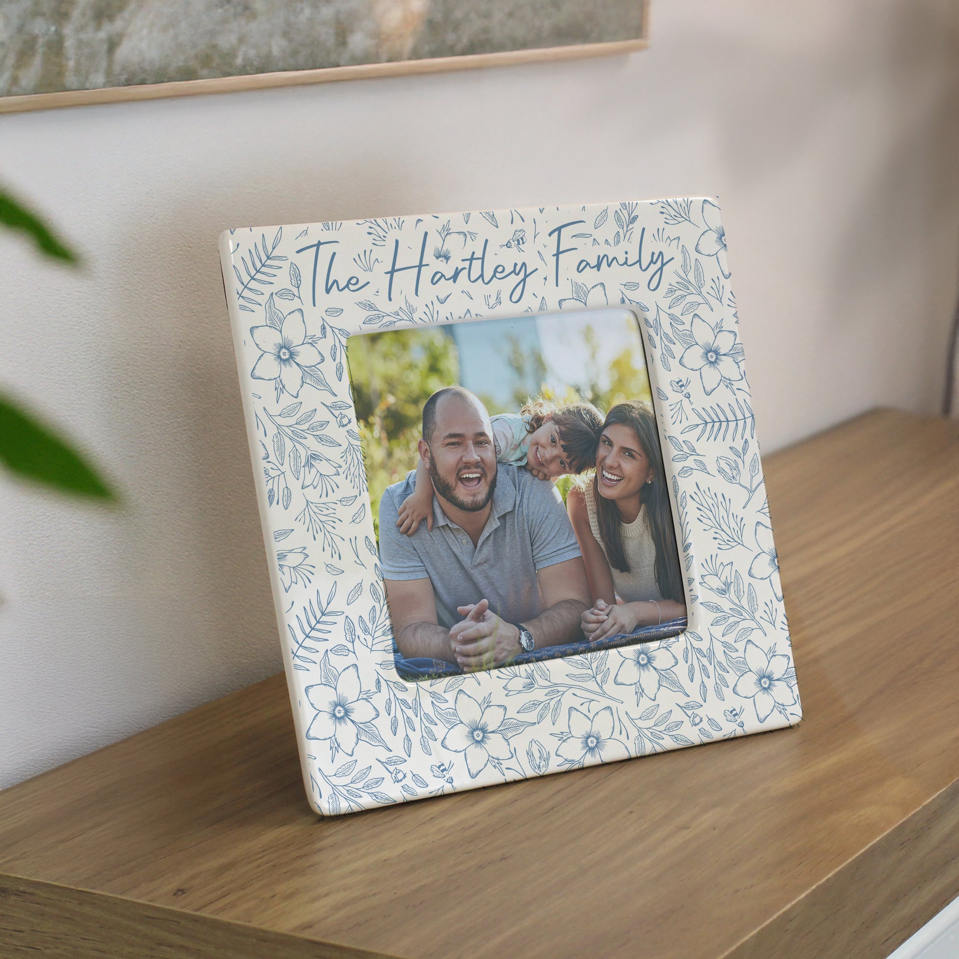 Decorative photo frame with floral design and family photo on a wooden surface