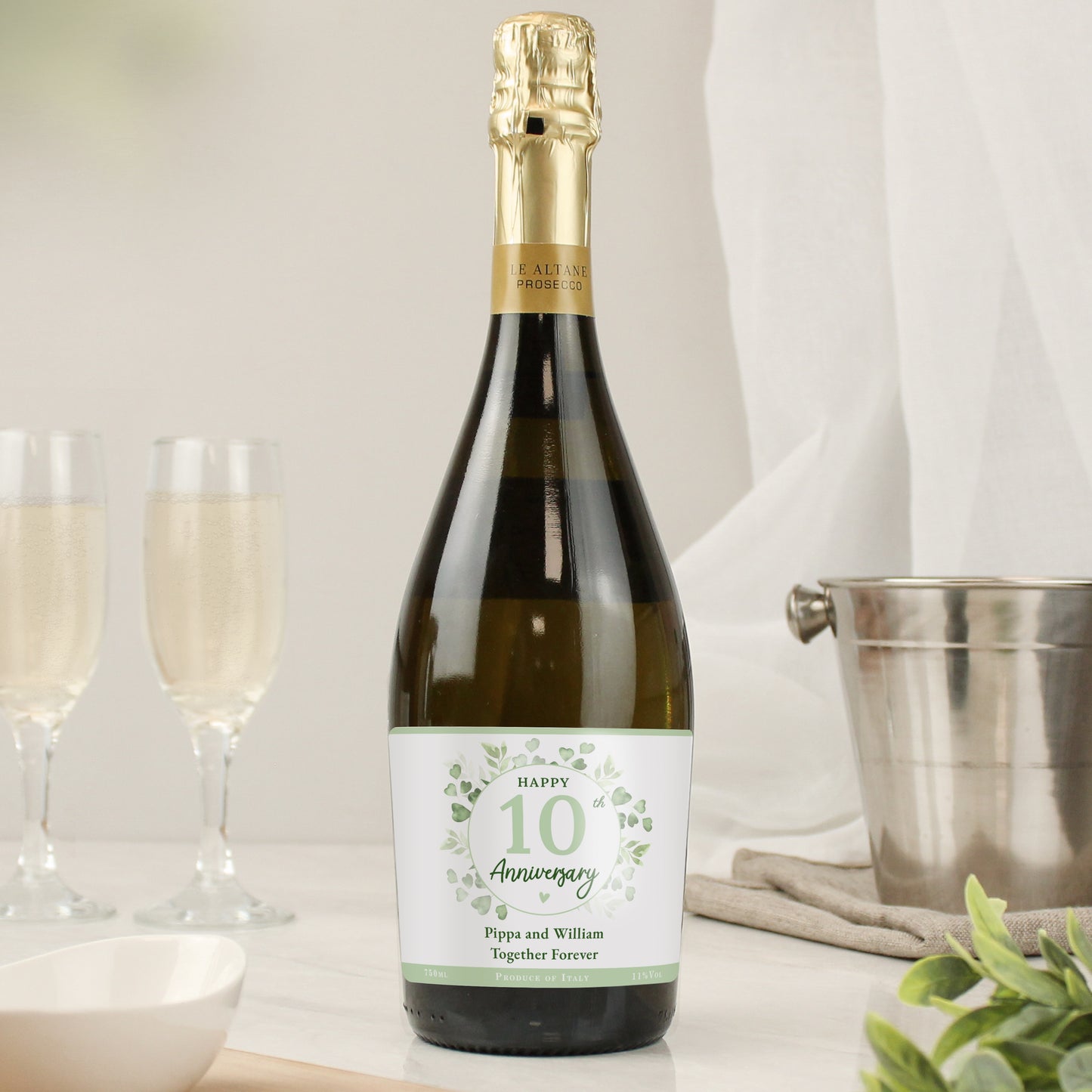 Bottle of prosecco with Happy 10 Anniversary label shown with wine bucket and flutes