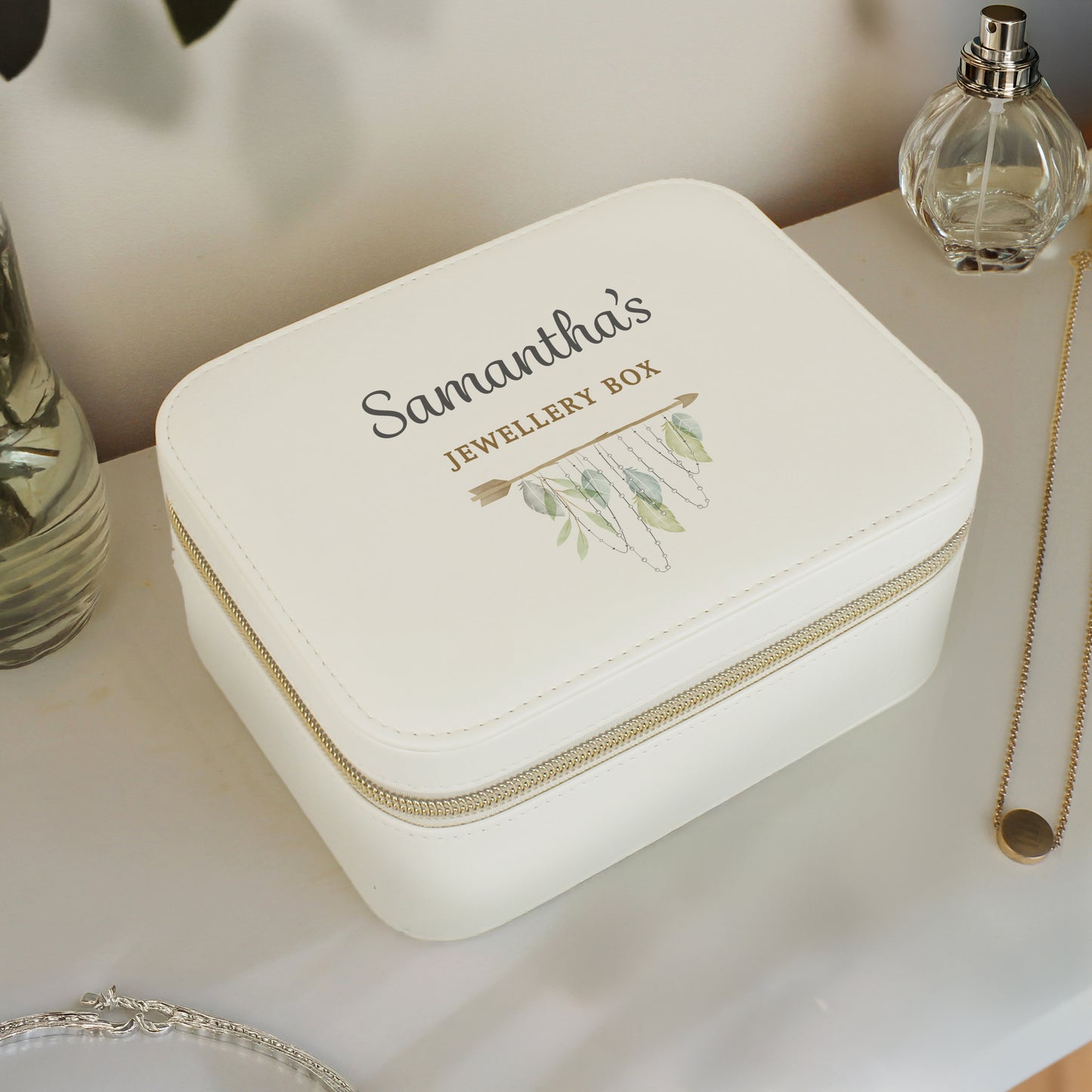 White jewelry box with 'Samantha's Jewellery Box' engraving on a table with a necklace and perfume bottle.