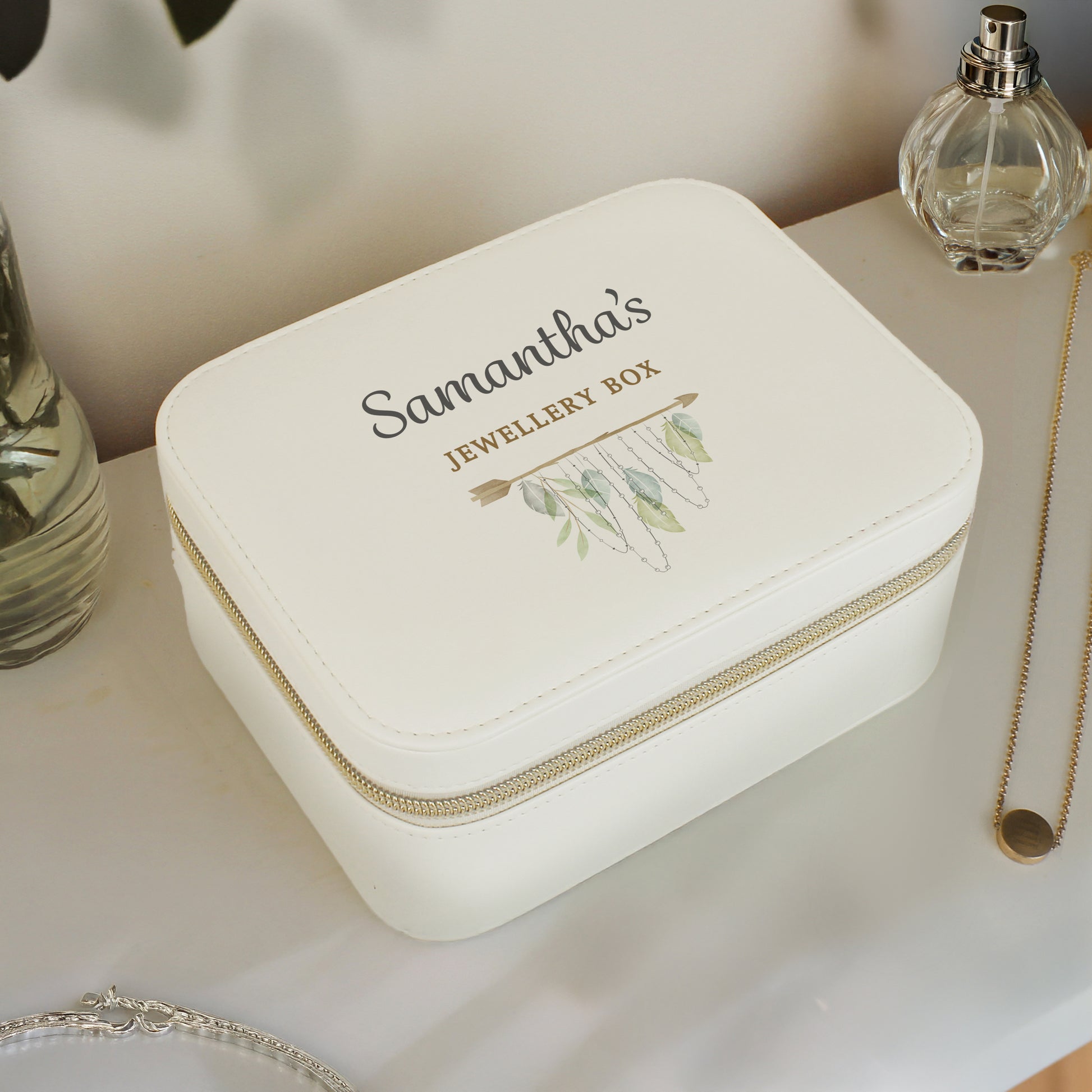 White jewelry box with 'Samantha's Jewellery Box' engraving on a table with a necklace and perfume bottle.