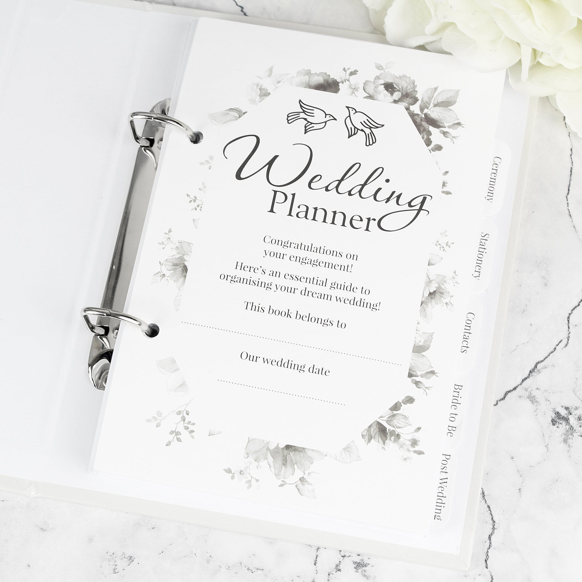 Wedding planner book on a marble surface with floral designs