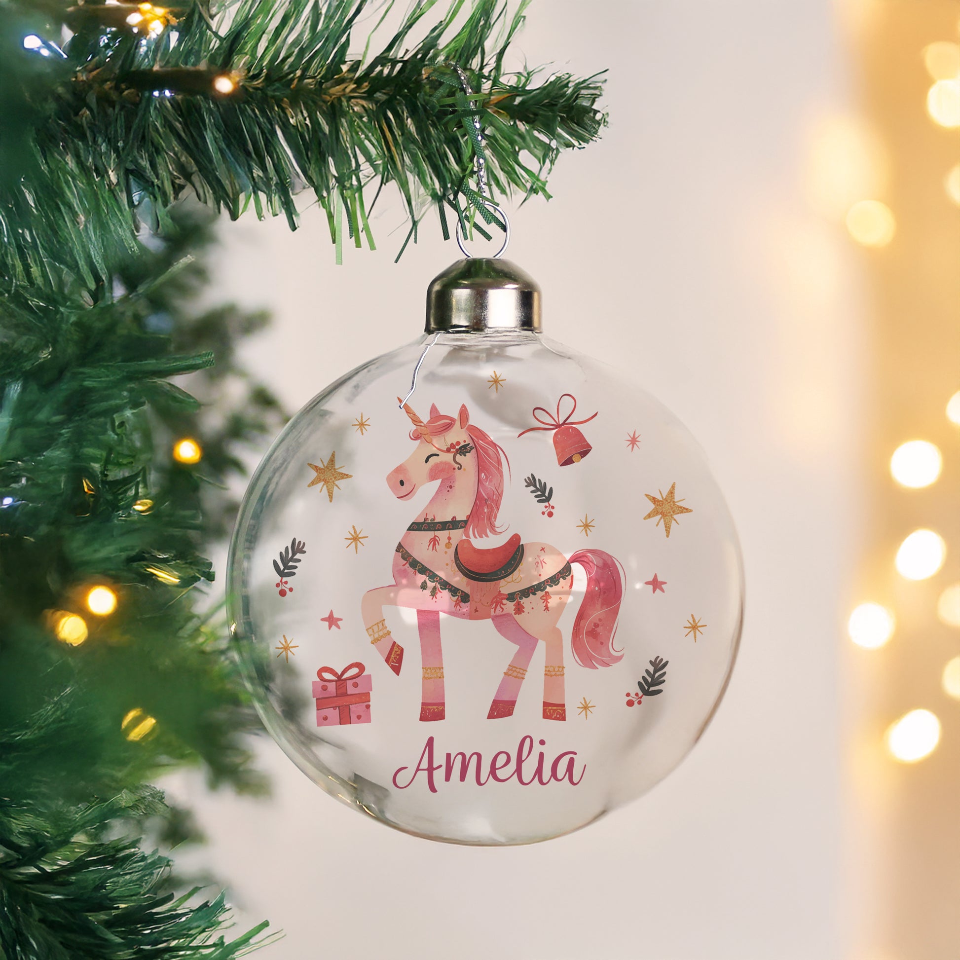 Glass Christmas bauble hanging on a tree. Unicorn image and personalised text in pink reads Amelia