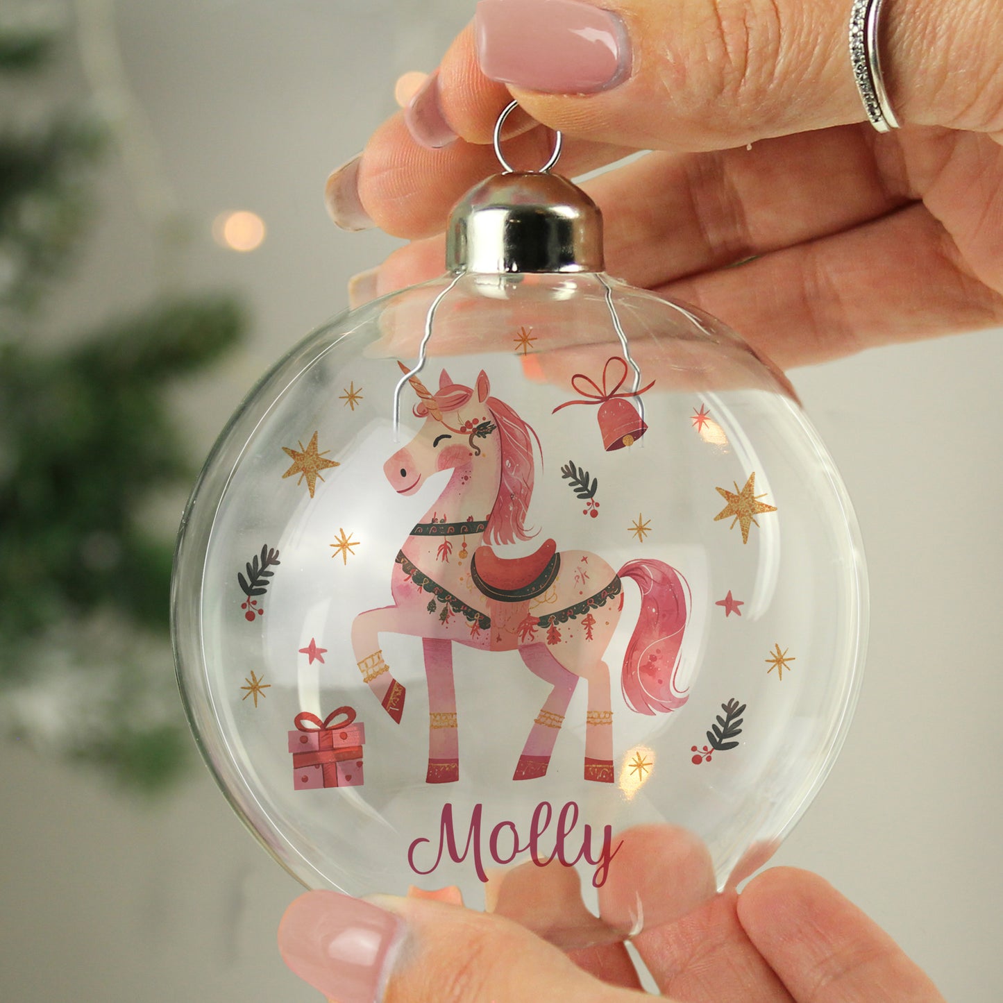 Clear Christmas ornament with a pink unicorn design and 'Molly' text, held by a hand.