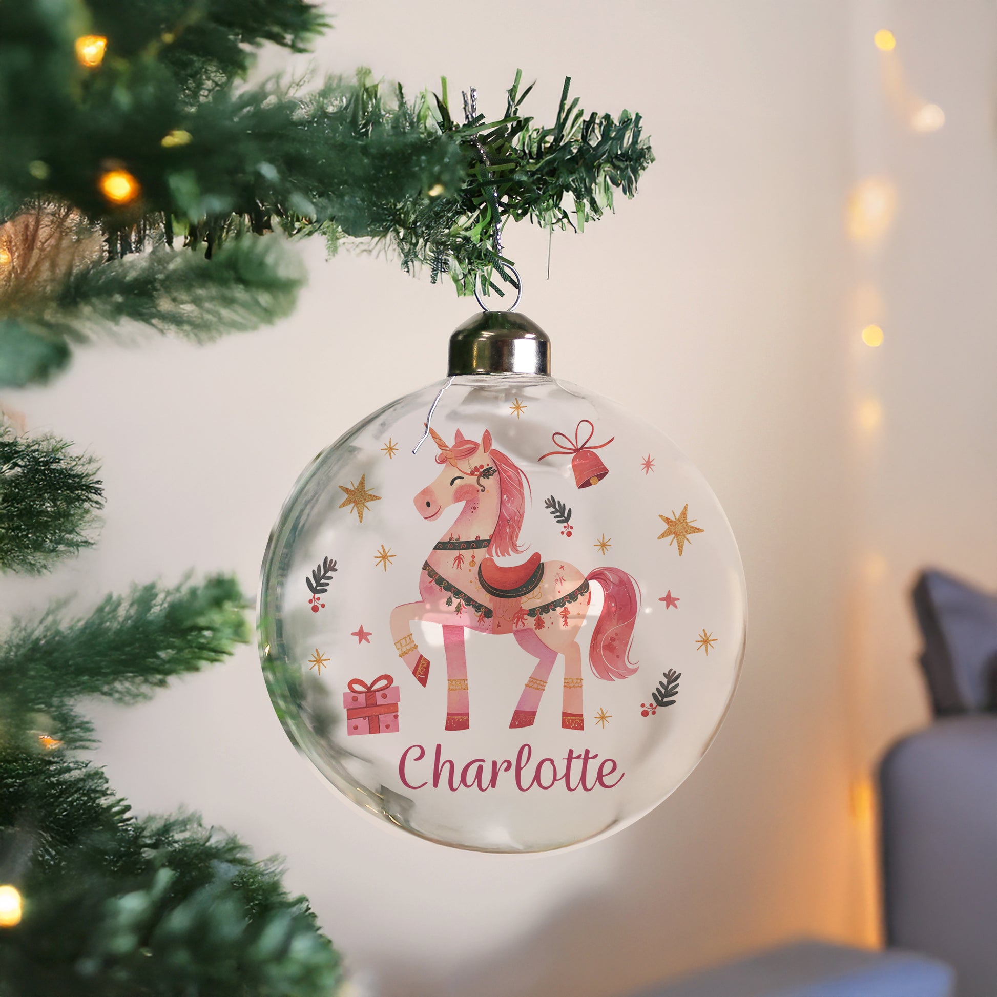 Decorative Christmas ornament with a unicorn design and 'Charlotte' text, hanging on a tree.