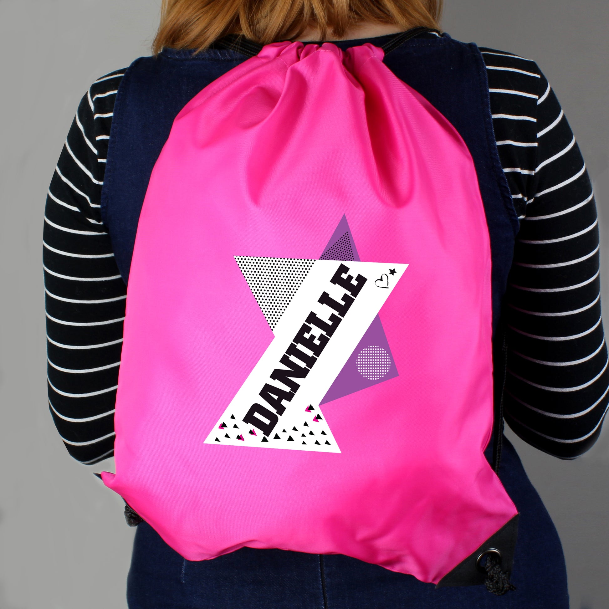 Person wearing a pink drawstring bag with a personalized design on a gray background