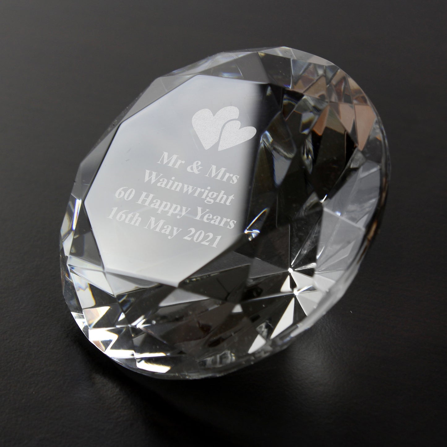 Clear paperweight with cut edges and personalised diamond anniversary message on a black background.
