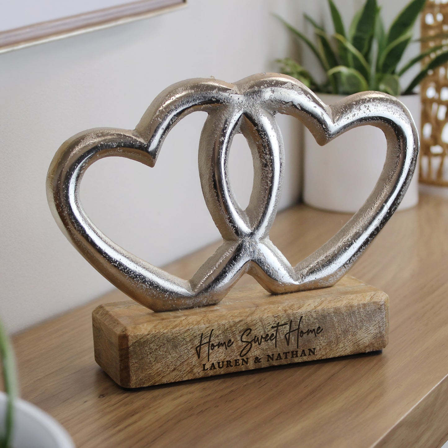 Decorative double heart sculpture on a wooden base with 'Home Sweet Home' engraving, placed on a wooden surface.