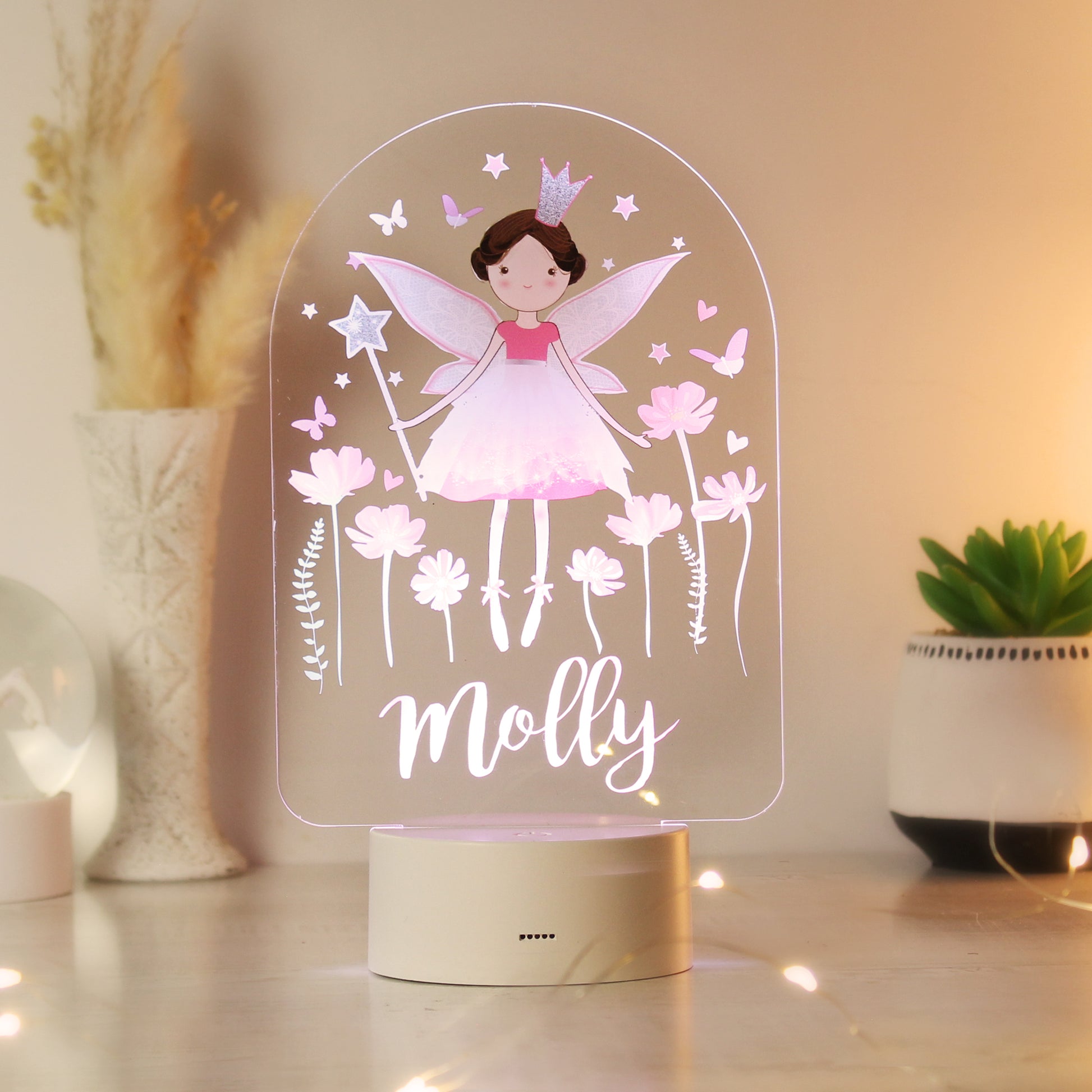 Fairy-themed night light with 'Molly' on a wooden surface with plants in the background