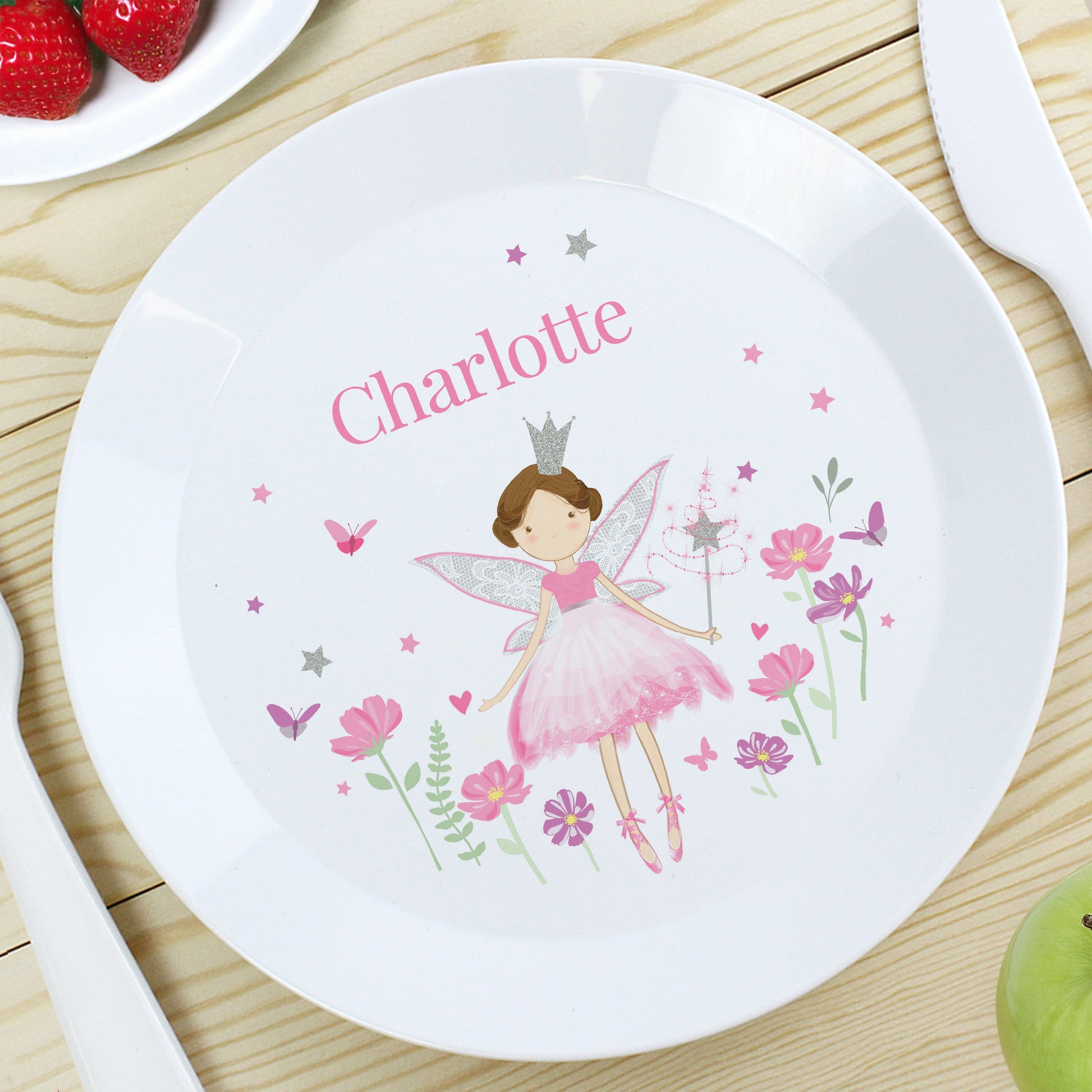 Children's plate with fairy design and name 'Charlotte' on a wooden table.